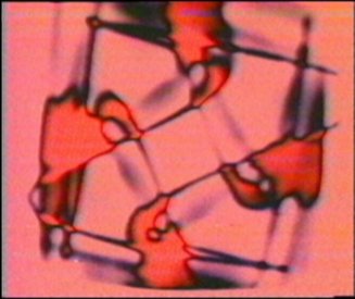 Frame from Video MetaProgramming One. Colourised computer generated Lissajous and feedback. (1974)