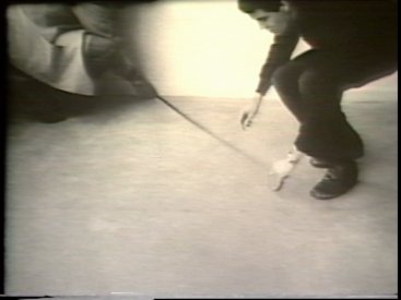 Still from Sequence 16 of Idea Demonstrations. Peter Kennedy and Mike Parr mark a perspictival line from the top left corner of the camera image.  