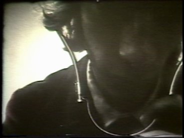 Still from Sequence 9 of Idea Demonstrations. Ian Stocks records the sound of the camera with a stethoscope.
